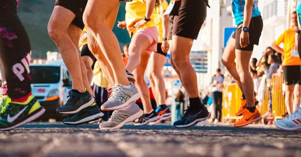 Runners before a race showing the bottom half of the legs and running trainers.