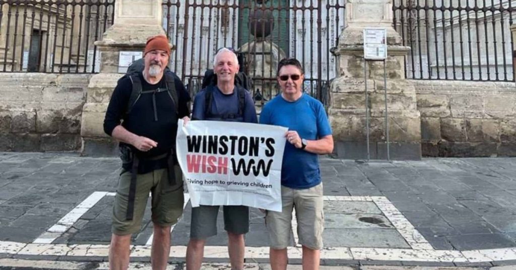 Barry and Alec walking in Spain holding a Winston's Wish sign