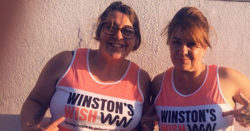 Two female supporters smiling at the camera in their Winston's Wish vests
