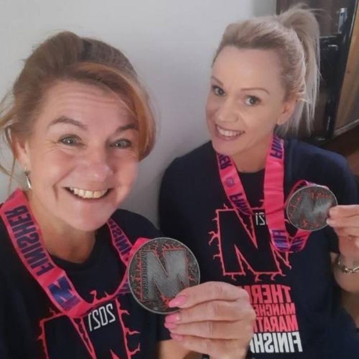 Marie with her friend holding their finisher medals