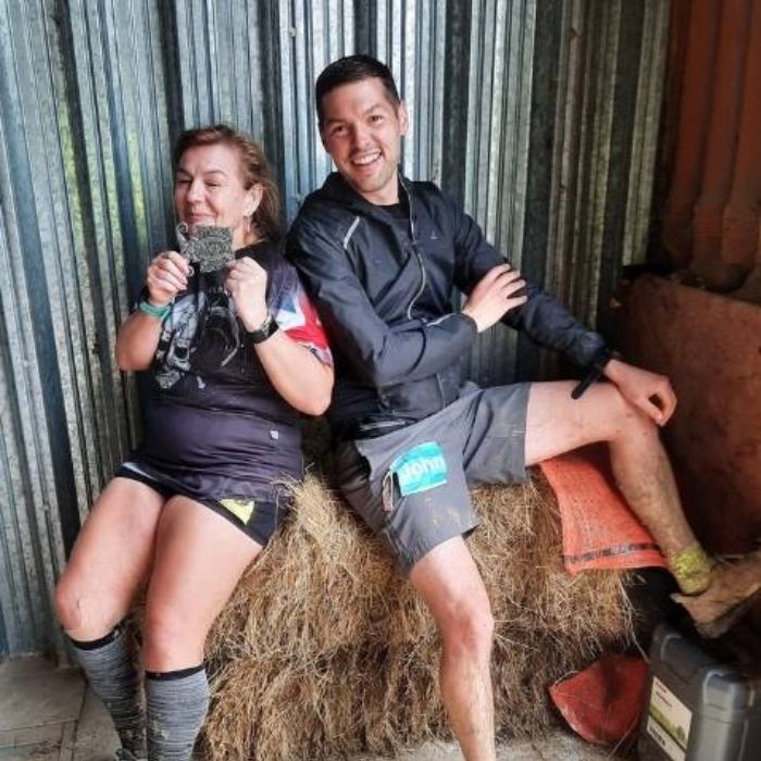 Marie with a male friend holding up another finisher medal