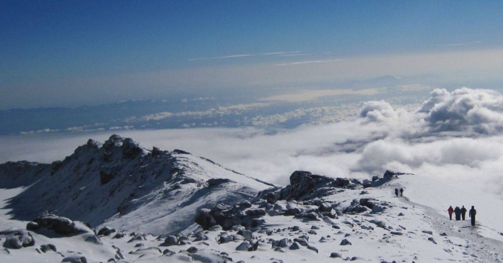 Wide pan of the top of Kilimanjaro with a sheet of snow covering the top