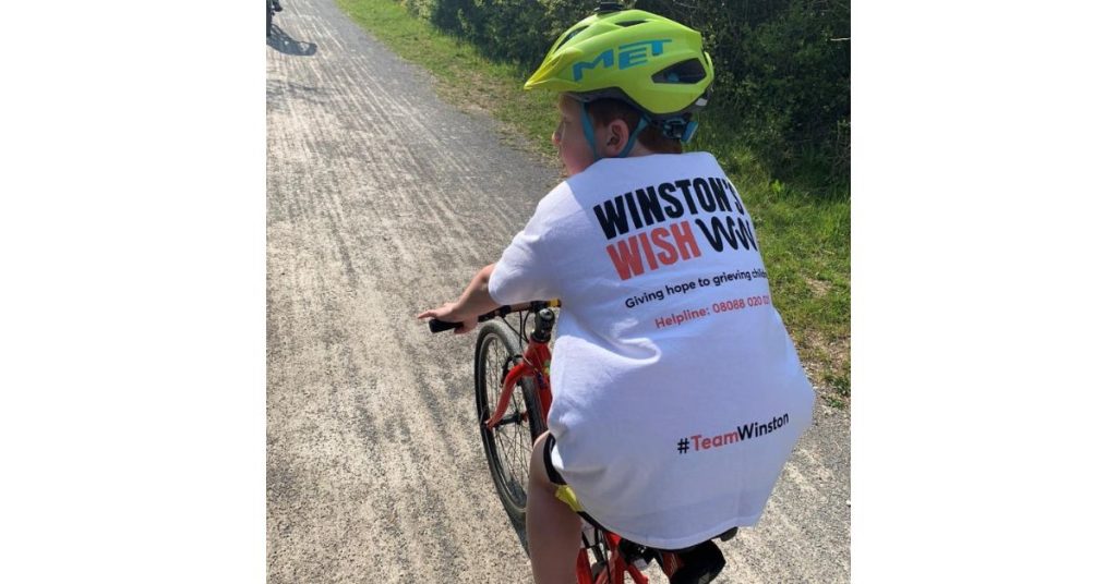 Thomas cycling down the country path with his Winston's Wish t-shirt on display