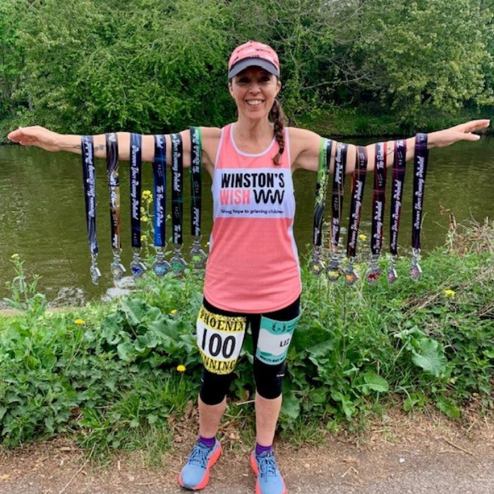 Liz with her 12 medals from her 12 half marathon challenge